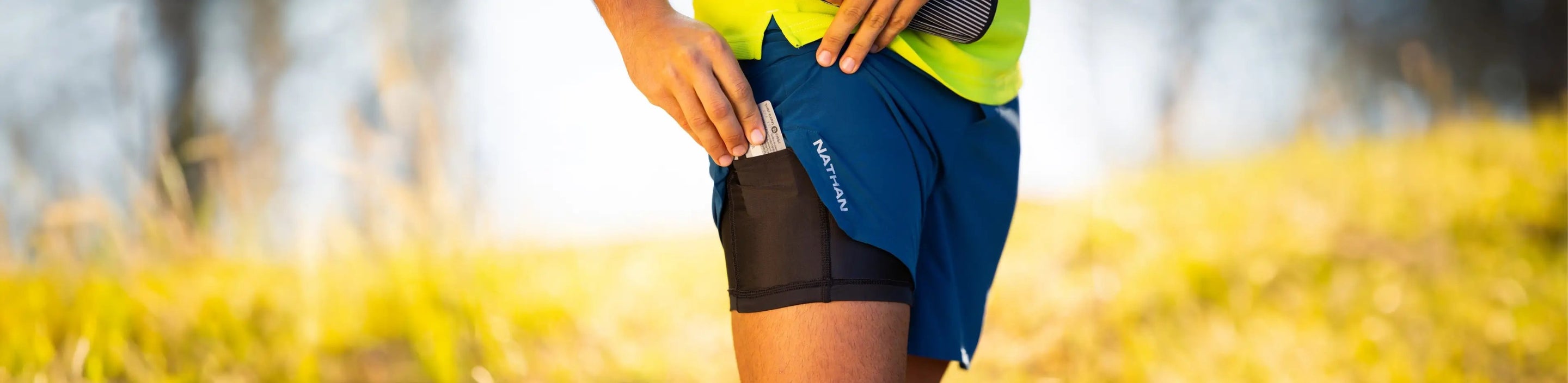 man wearing Nathan Shorts running shorts putting a cell phone in the liner pocket