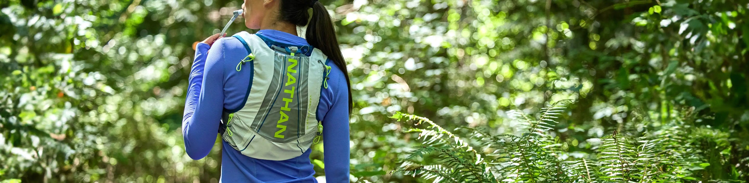 woman wearing Nathan Sports hydration pack surrounded by greenery