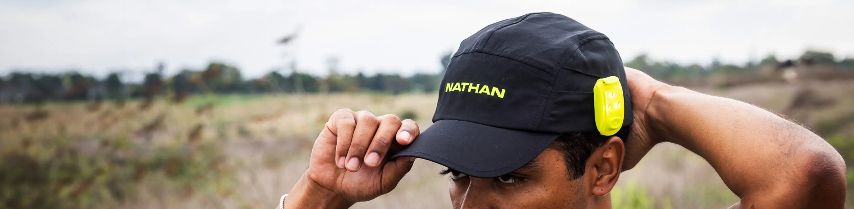 male athlete wearing Nathan Sports Run Cool Stash Hat with safety light attached