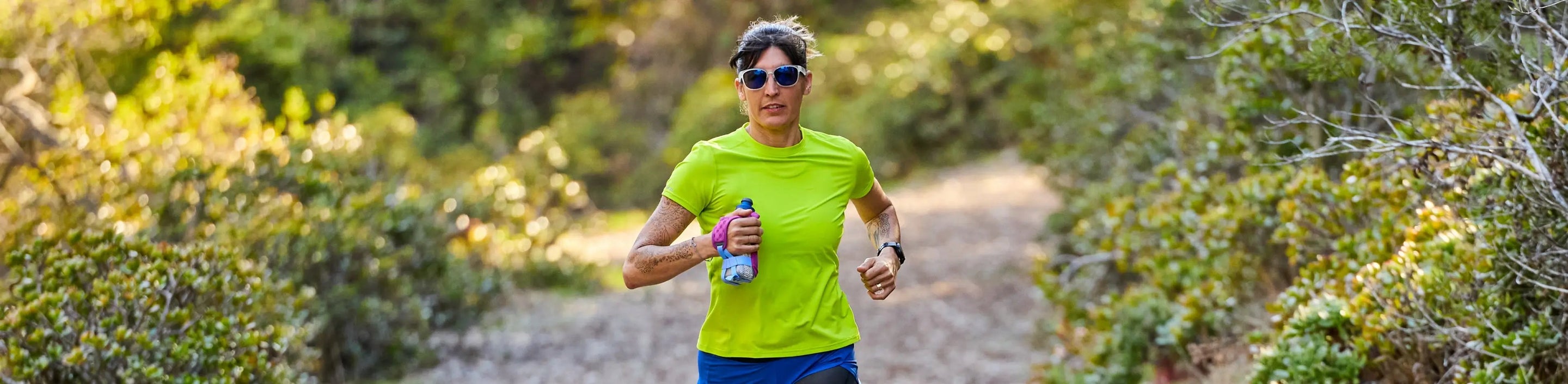 woman running in Nathan Sports Short Sleeve Shirt using handheld water bottle