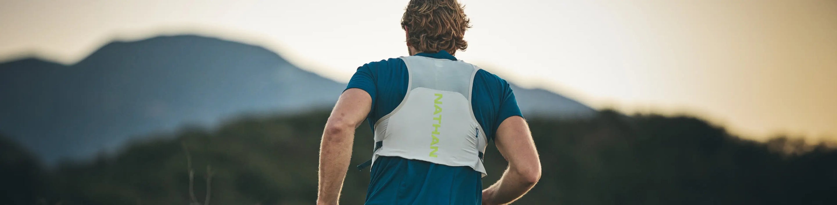 male runner with mountain landscape wearing Nathan Sports Hydration Pack