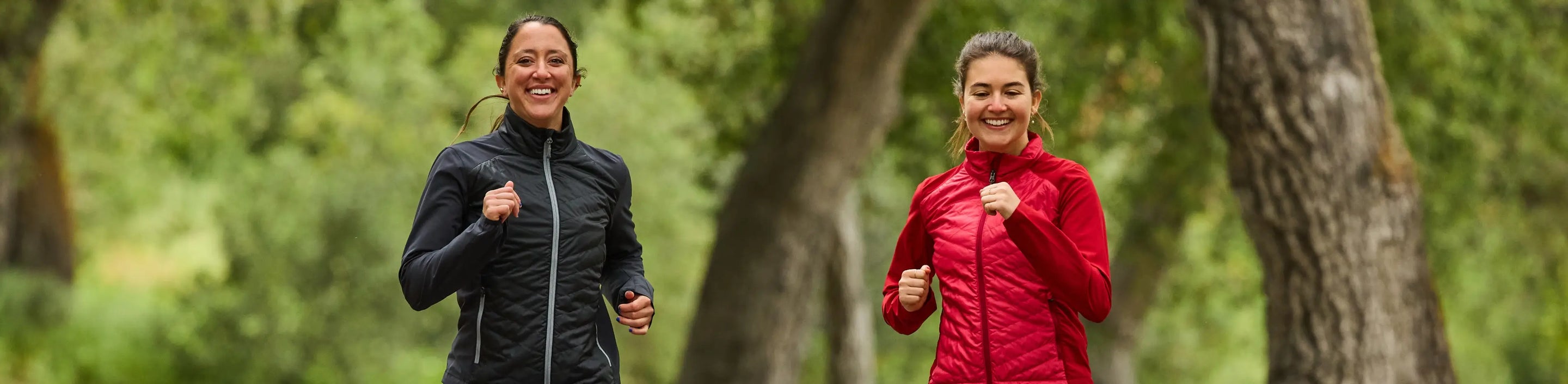 two runners wearing Nathan Sports jackets with trees in the background