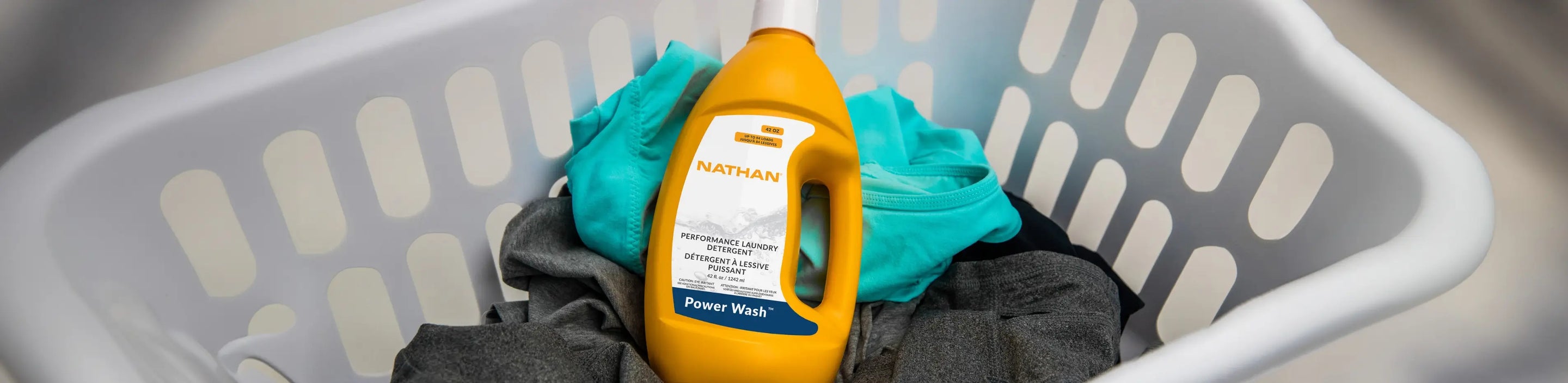 image of laundry basket with couple items of clothing and Nathan Sports bottle of laundry detergent