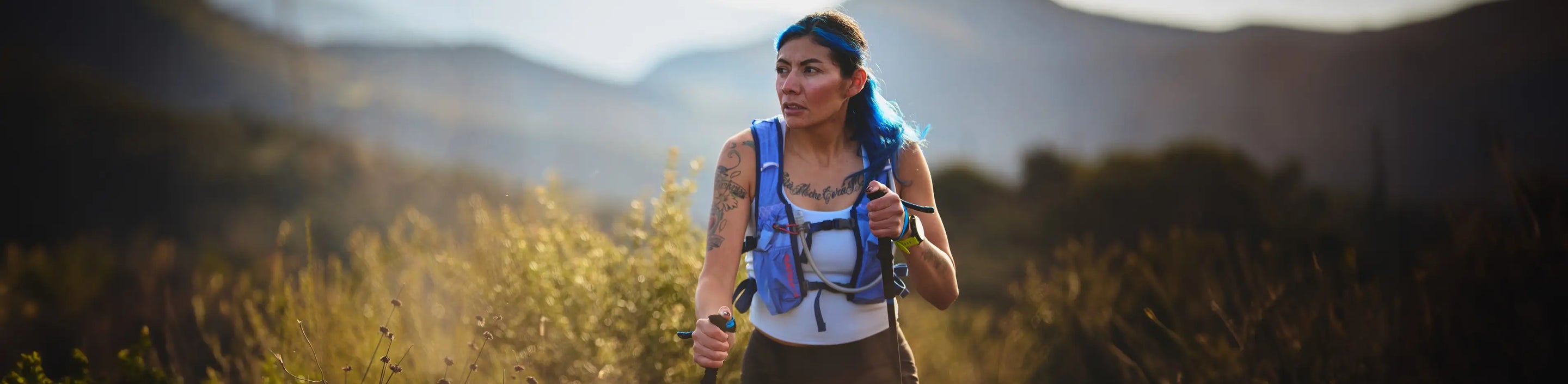 woman running with hazy mountain backdrop wearing Nathan Sports TrailMix 2.0 12 Liter Hydration Pack