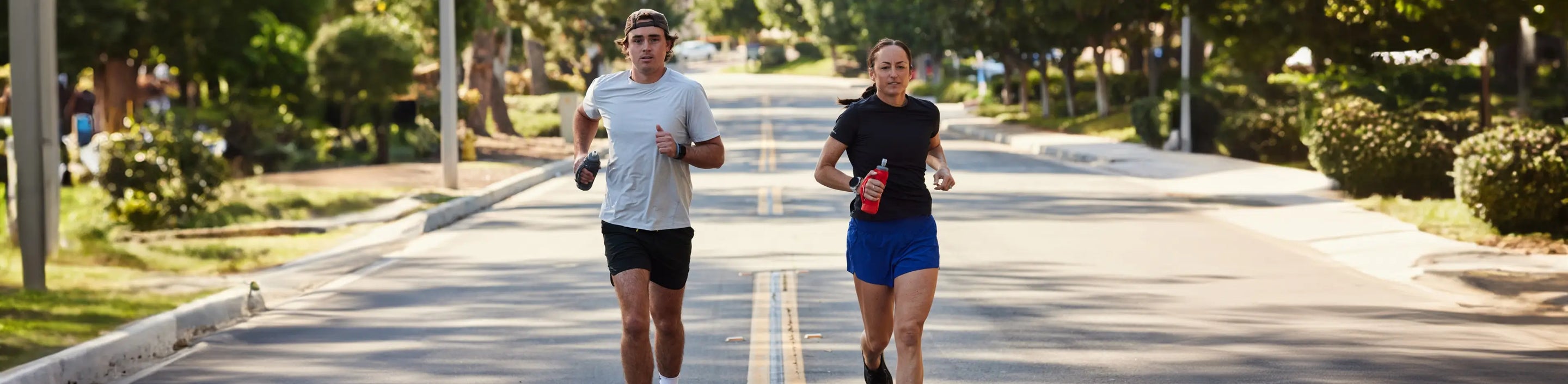 one male and one female on a road running in Nathan Sports short sleeve shirts and shorts