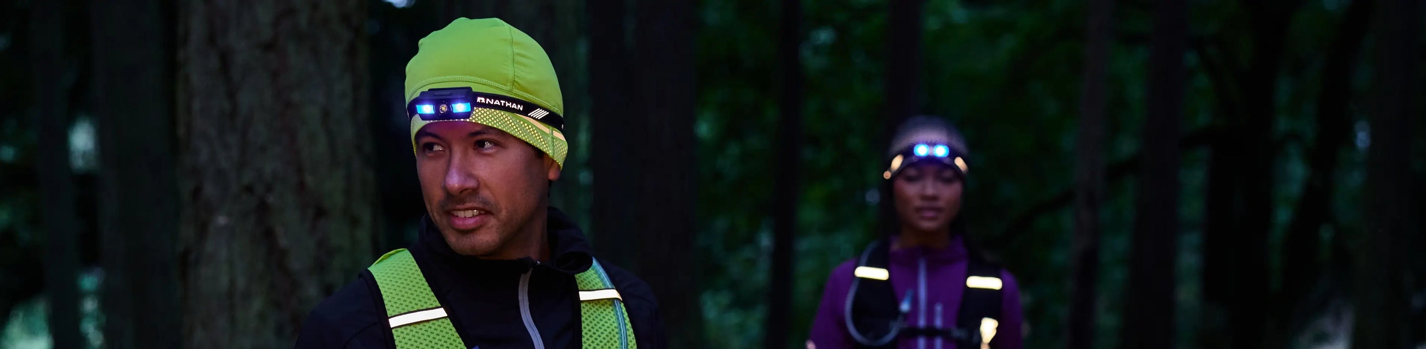 two runners wearing reflective gear and headlamps