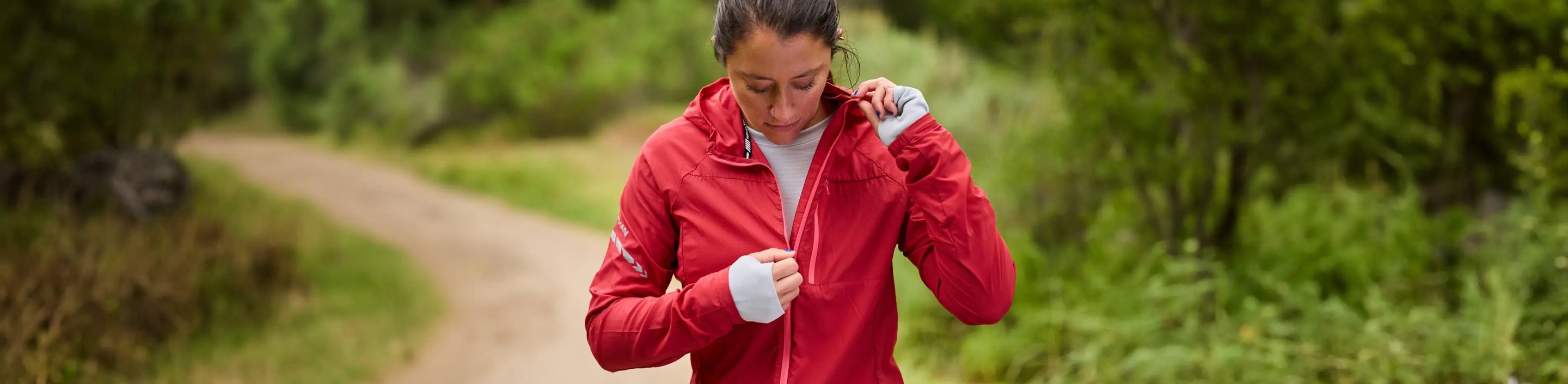 woman zipping up Nathan Sports Stealth Jacket in Deep Red