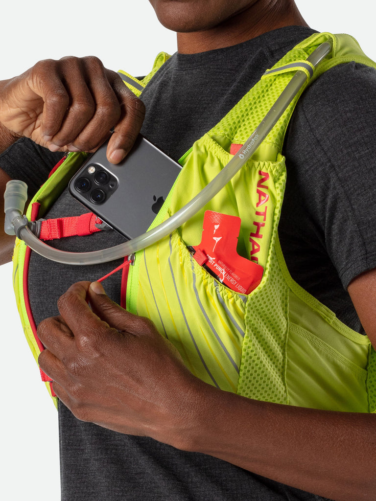 Nathan Pinnacle 12 Liter Women's Hydration Race Vest - Finish Lime/Hibiscus Red - Female Runner Pulling Cell Phone/Smartphone From Front Pocket