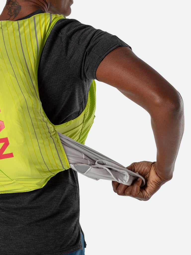 Nathan Pinnacle 12 Liter Women's Hydration Race Vest - Finish Lime/Hibiscus Red - Female Runner Pulling Clothing From Easy-Access Kangaroo Pocket