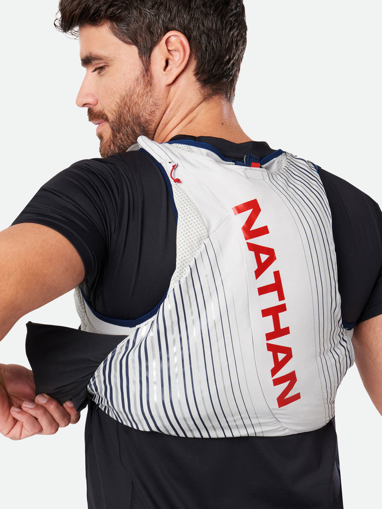 Nathan Pinnacle 12 Liter Unisex Hydration Race Vest - Caribbean Blue/Magenta - Male Runner Pulling Clothing From Easy-Access Kangaroo Pocket
