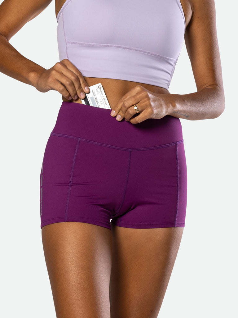 Nathan Women’s Interval 3” Bike Shorts – Plum Purple - On Model – Pulling Credit Card from Front Interior Pocket at Waistband