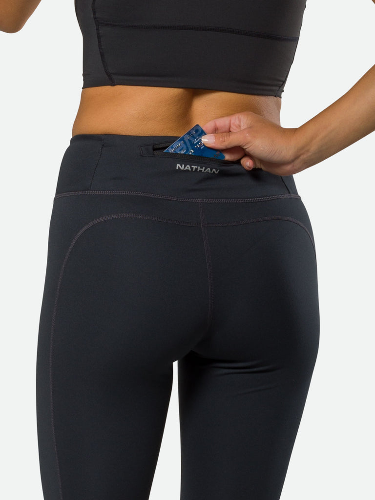 Nathan Women's Interval Running Tights - Black – On Model - Pulling Credit Card from Back Pocket