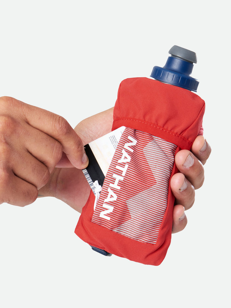 Nathan QuickSqueeze 12oz Insulated Hydration Handheld - Ribbon Red/White - Runner Pulling Out Credit Card From Pocket of Handheld