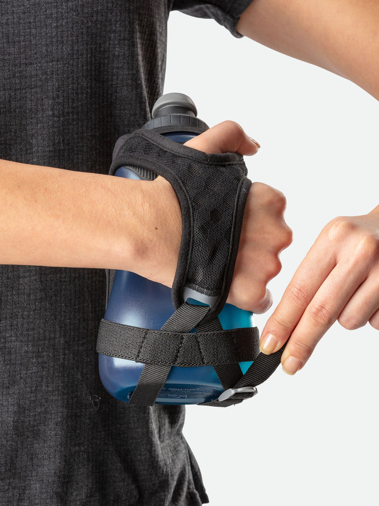Nathan QuickSqueeze 18oz Hydration Handheld - Black/Marine Blue - Runner Pulling Strap to Tighten Handheld Around the Palm